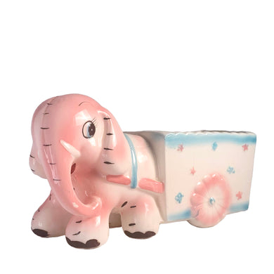 Adorable kitschy pink elephant pulling a wagon nursery planter. Crafted by Rubens Originals, Japan, 1950s. A sweet addition for your new addition. Use for tiny plants or repurpose to hold baby accessories.

In excellent as found vintage condition, no chips/cracks/repairs, normal crazing present.

Measures 6 1/2 x 2 1/2 x 3 1/2 inches