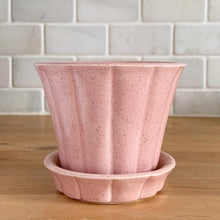 Load image into Gallery viewer, Vintage pink art pottery planter pot featuring a ribbed design and attached underplate. Crafted by McCoy Pottery, USA, circa 1940s. A collectible art pottery planter is perfect for a tiny houseplant, succulents or as part of your McCoy collection!  In vintage condition, several chips a crack. See photos for details.  Measures 4 1/8 x 3 1/2 inches

