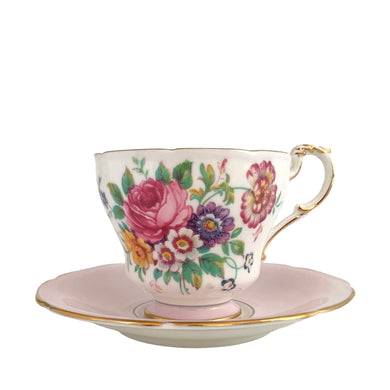 Stunning vintage teacup and saucer decorated with a pale shell pink interior features a bouquet of colourful flowers on the cup's exterior and centre of saucer, gold gilt scalloped rim. Crafted by The Paragon China Company, England, circa 1950s. A beautiful addition to your teacup and tableware collection!