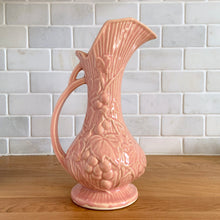 Load image into Gallery viewer, Beautiful vintage Art Deco pink pitcher vase features a unique handle and embossed grapevines. Crafted by McCoy Pottery, 1946. This vase is must for any art pottery collector. A lovely way to enhance your home&#39;s decor or to give as a gift!

In excellent vintage condition, no chips/cracks/repairs. Typical manufacturer&#39;s glaze misses/pops. Maker&#39;s mark on the bottom.

Measures 5 x 9 1/4 inches (incl. handle/spout)
