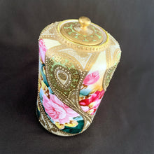 Load image into Gallery viewer, Absolutely exquisite one-of-a-kind hand painted porcelain lidded ginger jar, crafted by artisans in Japan circa late 1800s, early 1900s. It features sweeping panes of pink roses against a yellow and deep teal with alternating peacock feather-like shapes of gold gilt, heavily embellished with moriage, as is the lid. Nippon Porcelain,1891-1921.  
