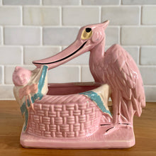 Load image into Gallery viewer, Vintage gloss pink glazed stork nursery ceramic planter with cold painted details. Crafted by McCoy Pottery, 1956. This rare planter is a must-have for any McCoy collector. It makes a wonderful gift for a baby shower and adds a nice touch of whimsy to your baby's nursery decor.

In excellent vintage condition, no chips/cracks/repairs, typical age-related wear to the cold paint. Marked on the bottom.

Measures 7 x 4 1/4 x 7 inches
