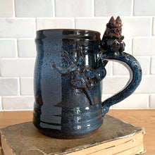 Load image into Gallery viewer, Rare vintage handmade Poseidon and Mermaid redware pottery mug finished in high fired two tone blue glaze on the exterior and a clear glazed interior. This large mug features a figural god of the sea wrapped around the exterior and mermaid in the interior of the mug. Crafted by KD Gandas, Lithuania 1990s. The perfect vessel for your favourite hot beverage!

In excellent condition with original sticker and impressed maker&#39;s mark.

Measures 6 1/4 x 4 1/4 x 6 1/2 inches (incl. handle)

Capacity 16 ounces
