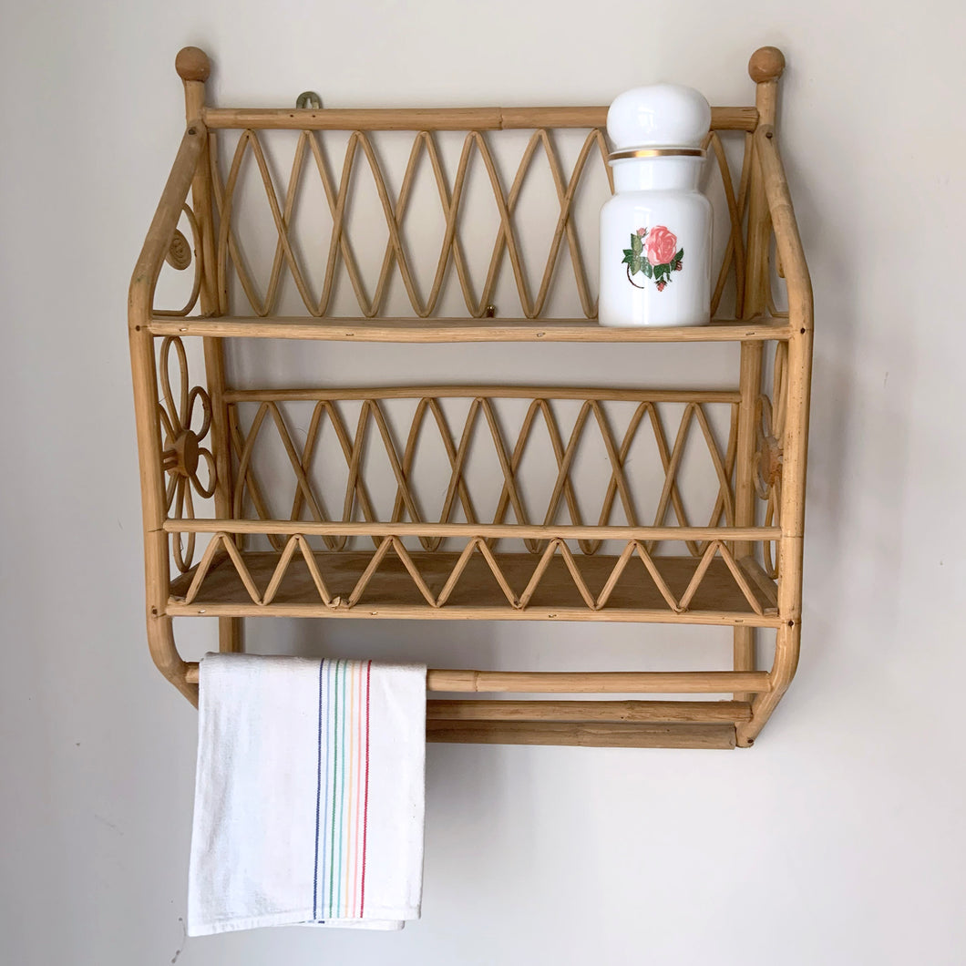 A vintage rattan 2-tier shelf with two towel bars featuring zigzag design, flower motifs and two metal brackets for ease of hanging. Perfect for storing smalls on the wall with boho charm!  In excellent used vintage condition with discolouration on the shelves from previous use.  Measures 15 3/4 x 6 x 19 1/2 inches   