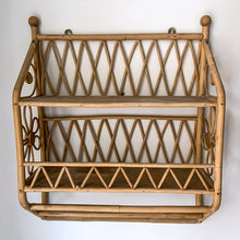 Load image into Gallery viewer, A vintage rattan 2-tier shelf with two towel bars featuring zigzag design, flower motifs and two metal brackets for ease of hanging. Perfect for storing smalls on the wall with boho charm!  In excellent used vintage condition with discolouration on the shelves from previous use.  Measures 15 3/4 x 6 x 19 1/2 inches   
