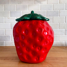 Load image into Gallery viewer, Rare vintage retro figural red strawberry cookie jar, topped with green lid. Crafted by McCoy Pottery, USA, 1970s. A good sized stoneware canister for a large batch of cookies that will look great as part of your kitchen decor!

In vintage condition, no chips/cracks/repairs, scuffing at the rim of the strawberry. Maker's mark on bottom.

Measures 7 1/4 x 9 3/4 inches

