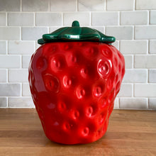Load image into Gallery viewer, Rare vintage retro figural red strawberry cookie jar, topped with green lid. Crafted by McCoy Pottery, USA, 1970s. A good sized stoneware canister for a large batch of cookies that will look great as part of your kitchen decor!

In vintage condition, no chips/cracks/repairs, scuffing at the rim of the strawberry. Maker's mark on bottom.

Measures 7 1/4 x 9 3/4 inches
