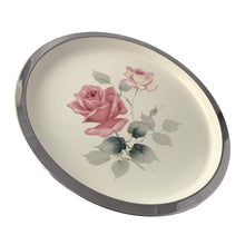 Load image into Gallery viewer, Vintage round metal serving tray featuring an enamled design of pink roses on a cream ground, with polished rim. Crafted by Cassidy's Ltd. Canada, 1960s. A gorgeous way to serve your guests or use as decor.

In excellent condition. Original sticker.

Measures 12 1/2 inch diameter
