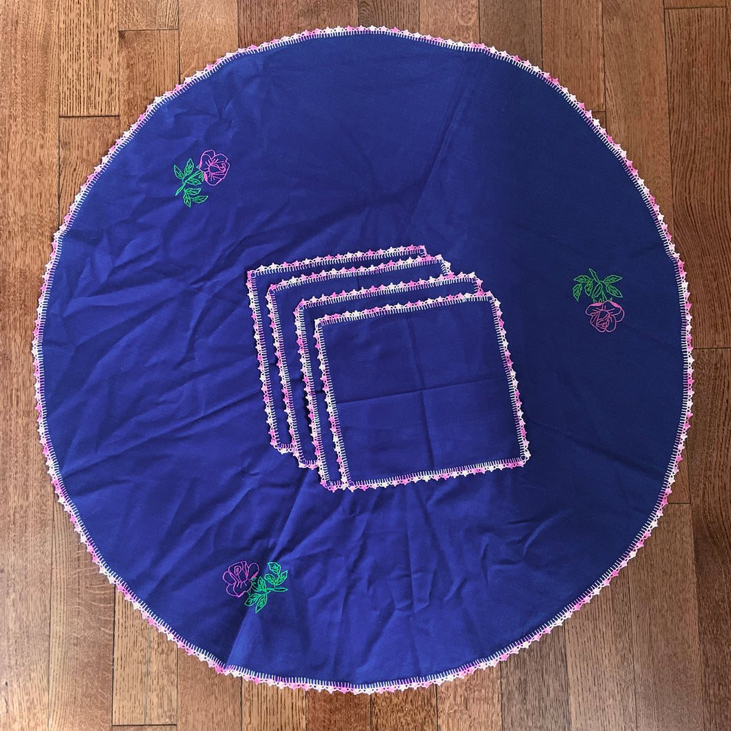 This beautiful vintage set comes with a chic rounded navy blue table cloth, hand-embroidered with a delicate pink crochet edge. The set also includes four matching napkins. An elegant statement piece for any occasion!  All pieces are in excellent condition.  Tablecloth diameter 35 inches  Napkins measure 10 x 10 inches