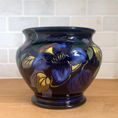 Vintage Royal Stanley Ware cobalt blue redware pottery jardiniere or planter, hand painted with a Clematis vine in shades of blue, purple, yellow, pink and green. Crafted by Colcolough & Co., England, 1919-1931. A lovely addition to your home's decor.

In excellent condition, no chips/cracks/repairs. Maker's mark on bottom.

Measures 5 1/2 x 5 inches