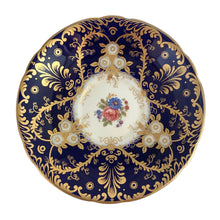 Load image into Gallery viewer, Vintage Royalty Bone China teacup and saucer features a hand painted cobalt blue interior on a white ground, lavishly decorated with gold gilt flowers and fluorishes, complemented by colourful florals in the bottom of the cup and centre of the saucer. Aynsley, England. 1934 - 1950s.  In excellent condition, no chips/cracks/repairs.  Teacup measures 4 x 2 1/4 Saucer measures 5 3/4
