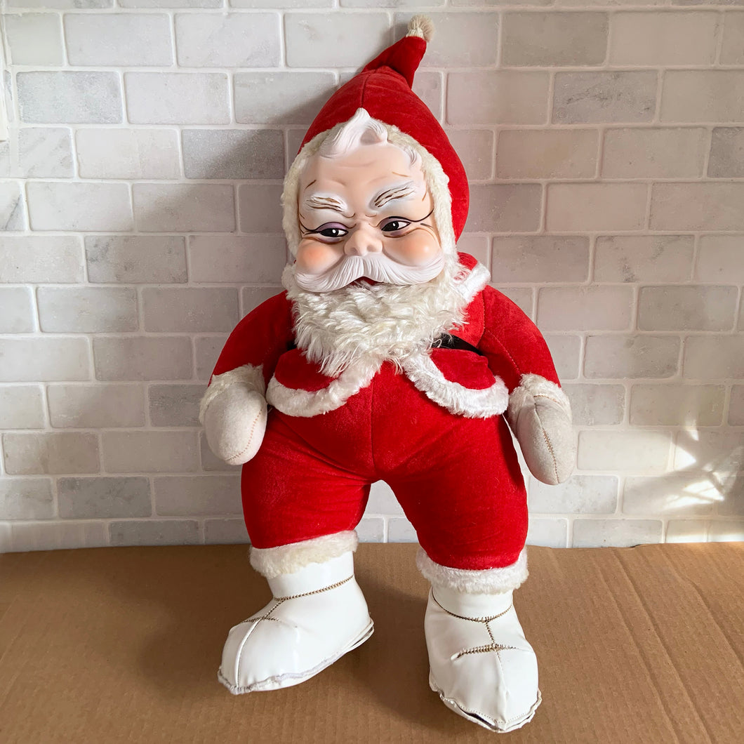 This rare adorable vintage mid-century era large rubber faced Santa Claus stuffed toy features a smiling side eyed face, a sheared velour red suit bordered with white plush trim, black vinyl belt, white velour hands, white vinyl-type blanket stitched boots. Crafted by the Rushton Company, USA, 1950s. A wonderful piece of Christmas nostalgia!

In as found vintage condition. The stitching on the boots have been repaired and could benefit from additional repair. Original tag.

Measures 13 1/2 x 24 1/2 inches