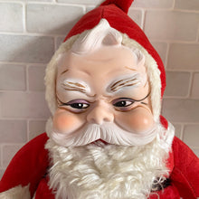 Load image into Gallery viewer, This rare adorable vintage mid-century era large rubber faced Santa Claus stuffed toy features a smiling side eyed face, a sheared velour red suit bordered with white plush trim, black vinyl belt, white velour hands, white vinyl-type blanket stitched boots. Crafted by the Rushton Company, USA, 1950s. A wonderful piece of Christmas nostalgia!

In as found vintage condition. The stitching on the boots have been repaired and could benefit from additional repair. Original tag.

Measures 13 1/2 x 24 1/2 inches
