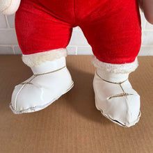 Load image into Gallery viewer, This rare adorable vintage mid-century era large rubber faced Santa Claus stuffed toy features a smiling side eyed face, a sheared velour red suit bordered with white plush trim, black vinyl belt, white velour hands, white vinyl-type blanket stitched boots. Crafted by the Rushton Company, USA, 1950s. A wonderful piece of Christmas nostalgia!

In as found vintage condition. The stitching on the boots have been repaired and could benefit from additional repair. Original tag.

Measures 13 1/2 x 24 1/2 inches
