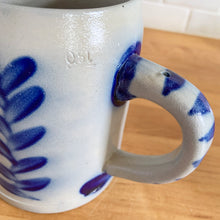 Load image into Gallery viewer, Salt glazed pottery has such a magical quality with its simple decorative style. This stein has a beautiful botanical design in cobalt blue which is striking against the light gray pottery. Crafted by Schilz in Germany. This stein is perfect for a mug of beer or repurpose to hold a small grouping of kitchen utensils or use as a pen/pencil holder. In excellent condition, no chips or cracks. Maker&#39;s mark on the side. Measures 3 3/4 x 5 inches.Capacity 1/2 litre
