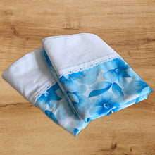 Load image into Gallery viewer, Dress your bed in this pair of retro blue and white floral &quot;Serenity&quot; patterned pillowcases. Each polyester/cotton pillowcase is finished with a white band at the edge with eyelet lace. Manufactured by Wabasso, Canada, circa 1970s. Create a restful slumber with these beautifully designed and well-made linens!  In excellent condition, free from tears. Colours are vibrant.  Measures 34 x 20 3/4 inches
