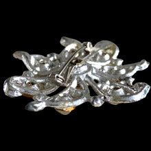 Load image into Gallery viewer, Side profile of vintage silver-tone pinwheel brooch showing depth of scrollwork frame and open rollover safety pin clasp
