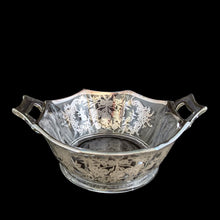 Load image into Gallery viewer, A lovely octagon shaped clear glass handled bowl featuring an art deco style decorative silver overlay of floral swags. The perfect size for candies or nuts and is easily repurposed as a trinket dish.   In excellent condition, free from chips/cracks and the silver overlay is intact.  Measures 6 5/8 x 3 1/8 inches (incl. handles)
