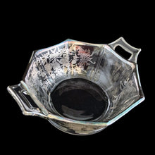 Load image into Gallery viewer, A lovely octagon shaped clear glass handled bowl featuring an art deco style decorative silver overlay of floral swags. The perfect size for candies or nuts and is easily repurposed as a trinket dish.   In excellent condition, free from chips/cracks and the silver overlay is intact.  Measures 6 5/8 x 3 1/8 inches (incl. handles)
