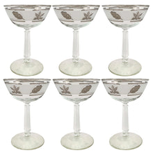 Load image into Gallery viewer, Vintage mid-century Silver Leaf champagne coupe or martini glass featuring silver leaves set on a frosted band, silver bands, grecian column stem. Crafted by Libbey Glass, USA, 1953 - 1978. These put the "glam" in glamourous — a stunning addition to your barware collection and perfect for ringing in the New Year with a toast! Also makes a wonderful wedding or housewarming gift for any cocktail enthusiast.

In excellent condition, no chips. Minimal wear.

Measures 3 3/4 x 5 5/8 inches

Capacity 7 ounces
