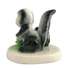 Load image into Gallery viewer, Vintage mid-century kitsch ceramic figures of a skunk mama and baby with a sweet pink flower on a stand. Crafted in Japan, circa 1950s. An adorable figurine to add to your mid-century animal figurine collection.  In excellent condition, no chips/cracks/repairs.  Measures 3 1/2 x 2 5/8 x 3 inches
