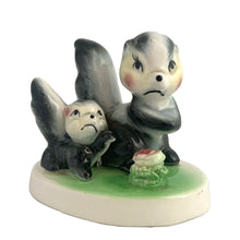 Load image into Gallery viewer, Vintage mid-century kitsch ceramic figures of a skunk mama and baby with a sweet pink flower on a stand. Crafted in Japan, circa 1950s. An adorable figurine to add to your mid-century animal figurine collection.  In excellent condition, no chips/cracks/repairs.  Measures 3 1/2 x 2 5/8 x 3 inches
