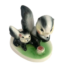 Load image into Gallery viewer, Vintage mid-century kitsch ceramic figures of a skunk mama and baby with a sweet pink flower on a stand. Crafted in Japan, circa 1950s. An adorable figurine to add to your mid-century animal figurine collection.  In excellent condition, no chips/cracks/repairs.  Measures 3 1/2 x 2 5/8 x 3 inches
