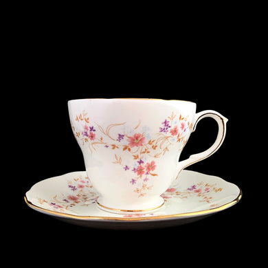 Vintage Spinney white bone china teacup and saucer features pink, purple and gold florals, trimmed in gold gilt. Crafted by Duchess, England, 1960s. A lovely way to enjoy a cuppa tea!

In excellent condition, no chips, cracks or repairs. Maker's mark on the bottom.

Measures 3 7/8 x 2 3/4 x 5 1/2 inches