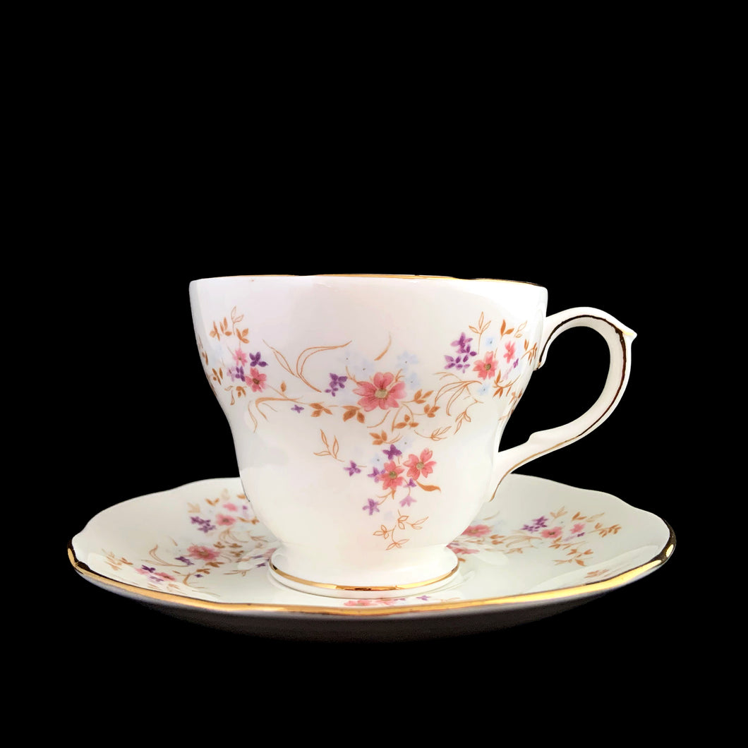 Vintage Spinney white bone china teacup and saucer features pink, purple and gold florals, trimmed in gold gilt. Crafted by Duchess, England, 1960s. A lovely way to enjoy a cuppa tea!

In excellent condition, no chips, cracks or repairs. Maker's mark on the bottom.

Measures 3 7/8 x 2 3/4 x 5 1/2 inches