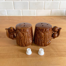 Load image into Gallery viewer, Vintage brown glazed ceramic salt and pepper shakers in the shape of tree stumps decorated with pine cones and a figural squirrel. The perfect addition to your kitschy cottage table decor!

In excellent condition, free form chips/cracks/repairs. New cork stoppers.

Measures 2 1/8 x 2 1/2 inches
