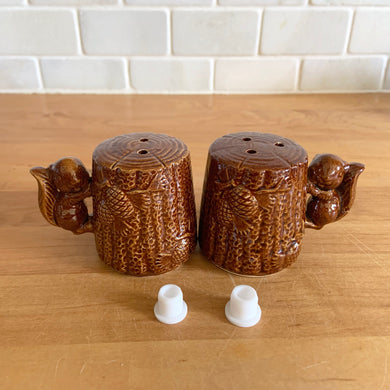 Vintage brown glazed ceramic salt and pepper shakers in the shape of tree stumps decorated with pine cones and a figural squirrel. The perfect addition to your kitschy cottage table decor!

In excellent condition, free form chips/cracks/repairs. New cork stoppers.

Measures 2 1/8 x 2 1/2 inches