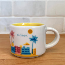 Load image into Gallery viewer, This sweet Starbucks collectible &quot;FLORIDA&quot; mini ceramic mug Christmas ornament from the &quot;You Are Here&quot; Collection, 2016. This white mug features a graphic skyline design in shades of yellow, orange and blue with yellow interior. Celebrate the sunshine state with an espresso!

In excellent condition, free from chips/cracks/wear.

Measures 2 3/8 x 1 7/8 inches

Capacity 2 ounces
