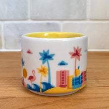 Load image into Gallery viewer, This sweet Starbucks collectible &quot;FLORIDA&quot; mini ceramic mug Christmas ornament from the &quot;You Are Here&quot; Collection, 2016. This white mug features a graphic skyline design in shades of yellow, orange and blue with yellow interior. Celebrate the sunshine state with an espresso!

In excellent condition, free from chips/cracks/wear.

Measures 2 3/8 x 1 7/8 inches

Capacity 2 ounces
