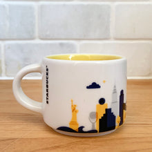 Load image into Gallery viewer, This sweet Starbucks collectible NEW YORK mini ceramic mug Christmas ornament from the You Are Here Collection, 2016. This white mug features a graphic skyline design in shades of yellow, orange and blue with yellow interior. Celebrate the Empire State with an espresso!

In excellent condition, free from chips/cracks/wear.

Measures 2 3/8 x 1 7/8 inches

Capacity 2 ounces
