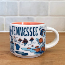 Load image into Gallery viewer, This sweet Starbucks collectible TENNESSEE mini ceramic mug Christmas ornament from the Been There Series Across the Globe Collection, 2016. This white mug depicting all things Tennessee in shades of yellow, orange and blue with yellow interior. Celebrate the The Big Bend State with an espresso!

In excellent condition, free from chips/cracks/wear.

Measures 2 3/8 x 1 7/8 inches

Capacity 2 ounces
