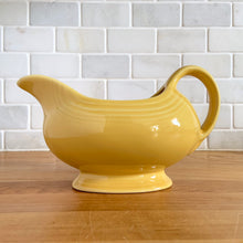 Load image into Gallery viewer, Fiestaware &quot;Sunflower&quot; yellow handled gravy sauceboat. The style and durability of this restaurantware can&#39;t be beat! Produced by the Homer Laughlin Company, USA, from 2001-. Dishwasher, oven and microwave safe and the great thing about the newer production is it is lead-free!  In excellent condition, free from chips/cracks. Marked on the bottom.  Measures 8 x 4 1/8 x 4 3/5 inches  Capacity 8 1/2 ounces
