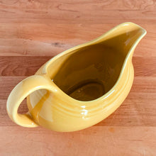 Load image into Gallery viewer, Fiestaware &quot;Sunflower&quot; yellow handled gravy sauceboat. The style and durability of this restaurantware can&#39;t be beat! Produced by the Homer Laughlin Company, USA, from 2001-. Dishwasher, oven and microwave safe and the great thing about the newer production is it is lead-free!  In excellent condition, free from chips/cracks. Marked on the bottom.  Measures 8 x 4 1/8 x 4 3/5 inches  Capacity 8 1/2 ounces
