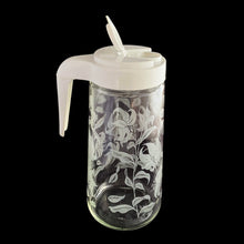 Load image into Gallery viewer, Vintage Tang promotional clear glass pitcher decorated with white enamel lilies and topped off with an open handled plastic lid with &quot;Tang&quot; impressed on the top. Crafted by Anchor Hocking, USA, circa 1970s. A great pitcher for your favourite beverage!  In excellent condition.  Measures 4 x 8 3/4 inches

