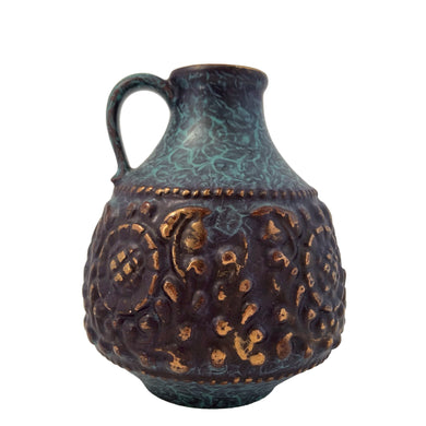 Vintage MCM handled ewer in deep teal, black and the embossed floral pattern in highlighted with gold, on shape 1633-15. Crafted by Jasba, West Germany, 1960s. A wonderful piece of mid-century era art pottery to enhance your home's decor.

In good vintage condition. Minor chip on the floral embossing, no cracks.

Measures 4 1/2 x 6 inches
