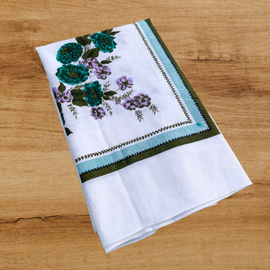 Give your table a touch of charm with this vintage mid-century 1950s white cotton linen tablecloth. This lovely linen features a pattern of teal, purple and green flowers, bordered by a band of deep green laurel leaves and teal stripes, plus a central circle of matching flowers. Add unique charm to your table and wow your guests!  In excellent, like new condition, free from stains/tears.  Measures 51 1/2 x 69 1/2 inches   