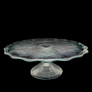This vintage clear pressed glass round cake stand features a textured pattern radiating from the central rum well and and finished with scalloped edge which is reminiscent of a pressed flower. Maker unknown. A beautiful piece to display cakes and desserts!  In excellent condition, free from chips. Unmarked.  Measures 12 x 4 1/4 inches