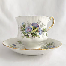 Load image into Gallery viewer, Stunning vintage white porcelain teacup and matching saucer decorated featuring thistle flowers in shades of purple and green plus gold gilt details with a spray of flowers on the interior of the teacup. Part of the English Flowers series produced by The Paragon China Company, England, circa 1950.  In excellent condition, free from chips/cracks/repairs. Marked on the bottom with single warrant stamp.  Teacup measures 3 1/8 x 2 3/4 inches  Saucer measures 5 3/8 inches
