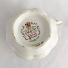 Load image into Gallery viewer, Stunning vintage white porcelain teacup and matching saucer decorated featuring thistle flowers in shades of purple and green plus gold gilt details with a spray of flowers on the interior of the teacup. Part of the English Flowers series produced by The Paragon China Company, England, circa 1950.  In excellent condition, free from chips/cracks/repairs. Marked on the bottom with single warrant stamp.  Teacup measures 3 1/8 x 2 3/4 inches  Saucer measures 5 3/8 inches
