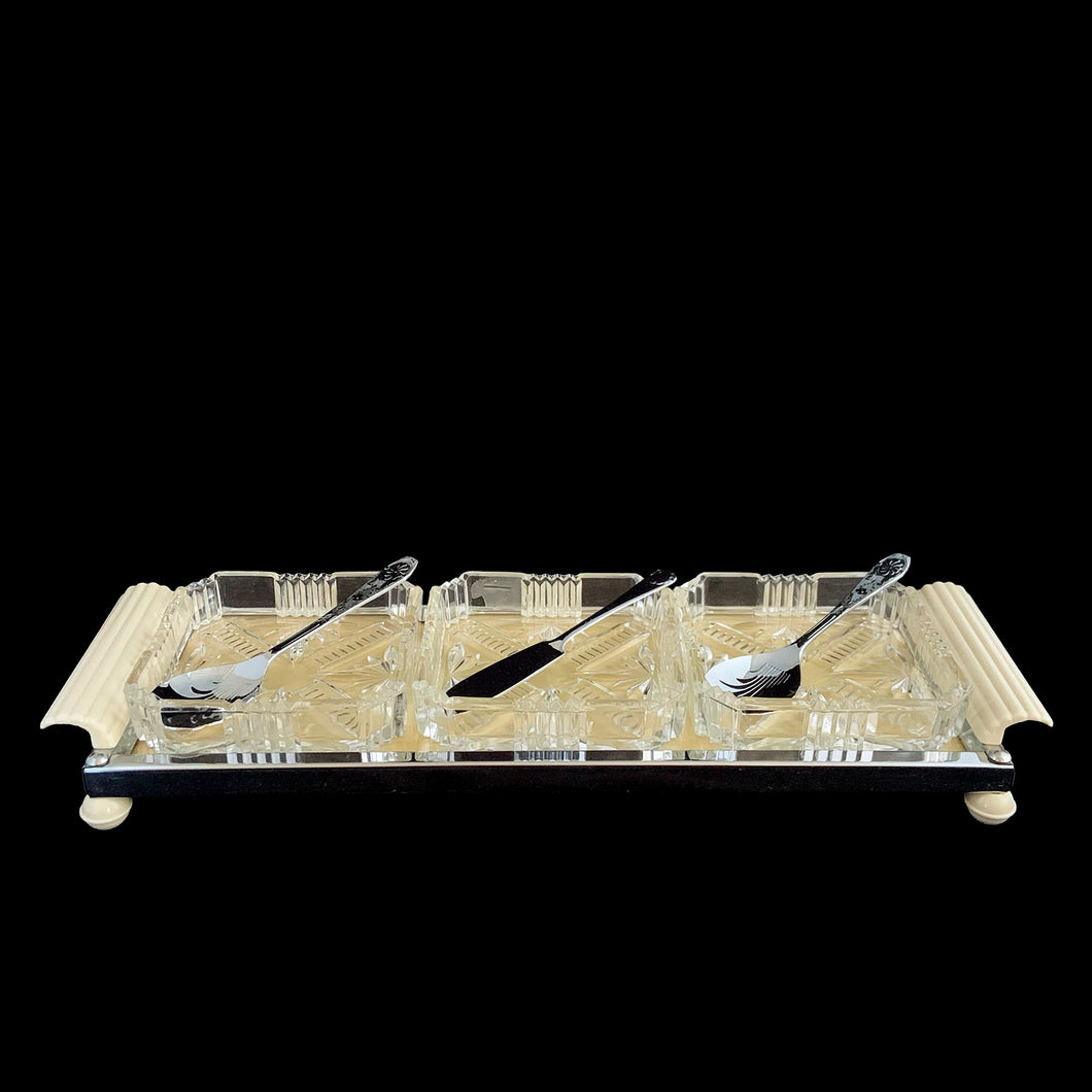 Vintage Art Deco 3-part relish tray featuring ribbed and curled bakelite handles and round feet, removable square cut glass inserts, with chrome-plated spoons and knife. Crafted by Zimco, England, 1950s. The epitome of elegance in entertaining for table or bar.

In excellent vintage condition no chips. There is discolouration on the paper under the glass in the tray, but it can easily be replaced.

Measures 14 x 4 3/4 x 1 3/4 inches, each glass insert measures 3 7/8 x 3 7/8 x 1 inches