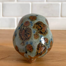 Load image into Gallery viewer, Vintage hand crafted Tonala folk art pottery owl figurine, hand painted and signed by artist Jorge Wilmot, Mexico. This owl has striking eyes, florals in ochre, brown and blue on a gray ground.

In excellent condition, no chips/cracks/repairs.

Measures 2 1/4 x 2 x 2 3/8 inches

