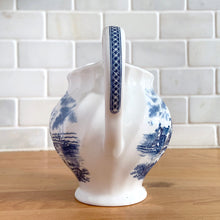 Load image into Gallery viewer, Vintage Tulip Time blue transferware ceramic creamer on white ground with swirl border features an intricate scene depicting a Dutch village, complete with windmills, cottages, and boats. Crafted by Johnson Brothers, England, 1962 - 1977. A lovely addition to your tablescape!

In excellent condition, no chips.

Measures 4 3/8 inches

Capacity 10 ounces
