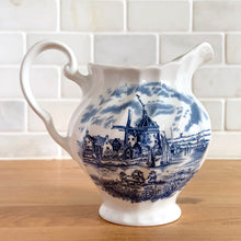 Load image into Gallery viewer, Vintage Tulip Time blue transferware ceramic creamer on white ground with swirl border features an intricate scene depicting a Dutch village, complete with windmills, cottages, and boats. Crafted by Johnson Brothers, England, 1962 - 1977. A lovely addition to your tablescape!

In excellent condition, no chips.

Measures 4 3/8 inches

Capacity 10 ounces
