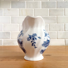 Load image into Gallery viewer, Vintage Tulip Time blue transferware ceramic creamer on white ground with swirl border features an intricate scene depicting a Dutch village, complete with windmills, cottages, and boats. Crafted by Johnson Brothers, England, 1962 - 1977. A lovely addition to your tablescape!

In excellent condition, no chips.

Measures 4 3/8 inches

Capacity 10 ounces
