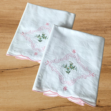 A lovely pair of vintage white cotton pillowcases, featuring elegantly design of hand embroidered turquoise flowers with green leaves, surrounded by cutwork and a border of pink flourishes and flowers, plus a finished pink scalloped edge. A gorgeous addition to your bed linens!  In excellent condition. New old stock.  Measures 31 1/2 x 19 1/2 inches   