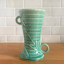 Load image into Gallery viewer, Vintage Art Deco gloss turquoise ring handled trumpet vase with leaves and berries on a ringed body. Crafted by McCoy Pottery, 1940s. This rare piece is must for any McCoy art pottery collector!

In as found vintage condition, no chips/repairs, tight hairline crack and crazing commensurate with age. Unmarked.

Measures 3 1/4 x 5 3/4 inches
